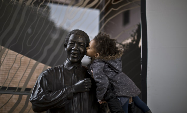 A South African girl held by her mother, kisses a statue of former president Nelson Mandela, at the Nelson Mandela Centre of Memory in Johannesburg on Monday - AP A South African girl held by her mother, kisses a statue of former president Nelson Mandela, at the Nelson Mandela Centre of Memory in Johannesburg on Monday - AP